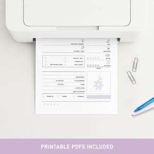 May include: A white printer printing a black and white plant care sheet. The sheet includes sections for common problems, pest/insects, frost protection, and other plant care information. Two silver paper clips and a blue pen are on the white surface.