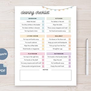 May include: A printable cleaning checklist with sections for bedroom, kitchen, living room, hallway, playroom, and bathroom. Each section has a list of tasks with checkboxes. The checklist is decorated with pastel color blocks and a banner of small flags. A pen rests on the right.