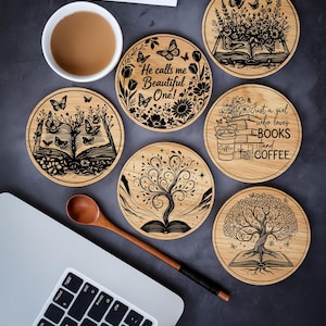 May include: Set of seven round wooden coasters with engraved designs. The designs include open books, butterflies, floral patterns, and the text "He calls me Beautiful One!" and "Just a girl who loves BOOKS and COFFEE."