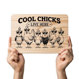 Könnte beinhalten: Ein Holzschild mit dem Text "COOL CHICKS LIVE HERE" in Schwarz. Das Schild zeigt sechs Cartoon-Hühner mit Sonnenbrillen. Die Hühner stehen in einer Reihe, jedes mit einem einzigartigen Muster und Design.