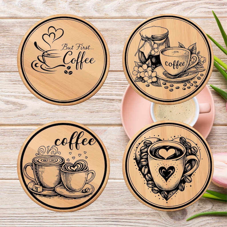 May include: Four round wooden coasters with black graphic designs. One coaster has the text "But First... Coffee" with a coffee cup illustration. Other coasters feature coffee cups, beans, and hearts.