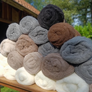 May include: A pile of rolled up wool yarn in various shades of brown, gray, and white. The yarn is arranged in a pyramid shape on a wooden table.