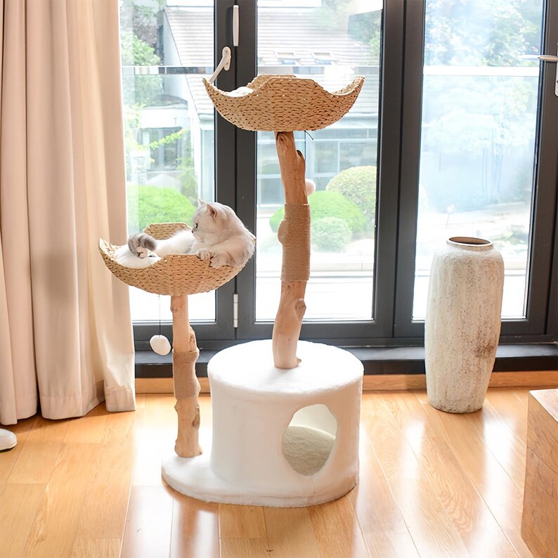 以下が含まれることがあります： 2 つのプラットフォーム、つめとぎポール、そして居心地の良い洞窟を備えた白い猫の木。プラットフォームは籐で編まれ、ポールはサイザルロープで包まれています。猫の木は窓と花瓶のある部屋にあります。