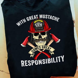 Puede incluir: Camiseta negra con una calavera que lleva un casco de bombero rojo y un bigote. El diseño incluye hachas cruzadas y el texto "WITH GREAT MUSTACHE COMES GREAT RESPONSIBILITY."