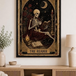 May include: A framed wall art print titled THE READER featuring a skeleton in a dark red robe sitting in a starry night scene. The skeleton holds a book and a teacup, surrounded by red roses, a lit candle, an open book, and a black cat.