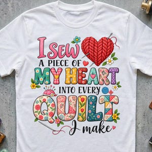 Puede incluir: Una camiseta blanca con un gráfico colorido y el texto I SEW A PIECE OF MY HEART INTO EVERY QUILT I make. El diseño incluye un corazón de hilo rojo, agujas de coser, patrones florales y letras estilo patchwork de varios colores.