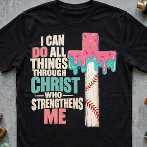 Puede incluir: Una camiseta negra de manga corta con el texto I CAN DO ALL THINGS THROUGH CHRIST WHO STRENGTHENS ME en rosa, blanco y turquesa. A la derecha, un gráfico de una cruz diseñado como una pelota de béisbol con glaseado rosa y turquesa.