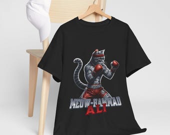 Puede incluir: Camiseta negra con un gráfico de un gato boxeador con guantes de boxeo rojos. El texto "MEOW-HAMMAD ALI" está impreso debajo del gato.