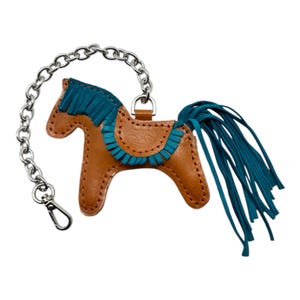 May include: A brown leather rocking horse keyring with a teal blue mane, tail, and saddle trim. The keyring has a silver chain.