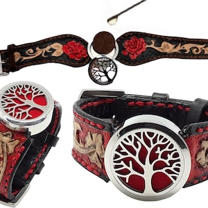 以下が含まれることがあります： 赤と金の刺繍が施された黒い革のブレスレット。ブレスレットには、木のデザインのシルバーチャームが付いています。チャームはエッセンシャルオイルのディフューザーです。