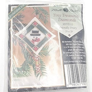 May include: A Mill Hill Tiny Treasured Diamonds cross stitch kit titled Friendly Frosty, MHTD10. The package features a diamond-shaped ornament design with a snowman, green border, and pink accents, including glass beads, crystal treasures, and floss.