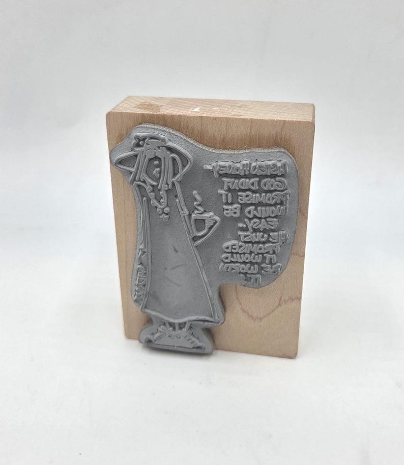 May include: A gray rubber stamp mounted on a wooden block. The stamp features a stylized illustration of a robed figure holding a cup, with text that reads "...would be easier..." and other text. The stamp is for crafts and art projects.