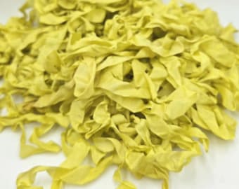 May include: A pile of yellow fabric strips, possibly ribbon or trim, with a slightly wrinkled texture. The fabric is a muted yellow color, and the strips are of varying lengths and widths. The image is taken from a slightly elevated angle.