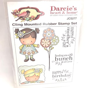 May include: A clear plastic package containing a cling mounted rubber stamp set. The set features illustrations of a girl, flowers, and text that reads "Happy Mother's Day", "Sending you a bunch of Love", and "Happy Birthday".