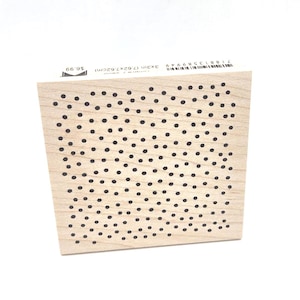 May include: A wooden stamp with a pattern of black dots. The stamp measures 3x3in (7.62x7.62cm). The stamp is light-colored wood with a black dot pattern. The stamp is used for crafts and scrapbooking.