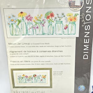 May include: A Dimensions Mason Jar Lineup counted cross stitch kit in plastic packaging. The kit includes presorted thread, 14 count white Aida, a needle, and instructions. The finished design features colorful flowers in various glass jars.