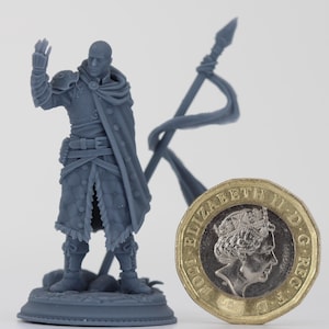 May include: A gray figurine of a man in a long coat, with a staff and a coin. The figurine is standing on a base. The coin is a gold-colored one pound coin.