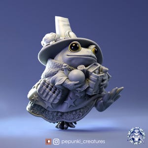 May include: A gray 3D printed figurine of a frog wearing a large hat with a white plume, a robe, and holding a book and a ball. The frog has large, round, yellow eyes.