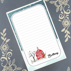May include: A lined notepad with a winter scene featuring a red barn, a tree with birds, and a deer. The notepad has a light blue border with the name "Brittany" in cursive.