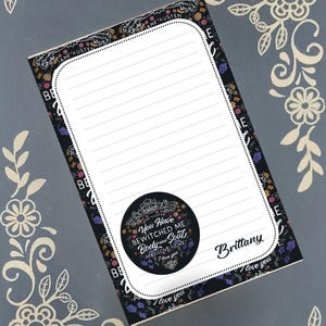 Peut inclure: Un bloc-notes ligné avec un motif floral et le texte "You Have Bewitched Me Body and Soul and I Love I Love I Love You." Le bloc-notes porte le nom "Brittany". Le bloc-notes est noir avec une bordure blanche.
