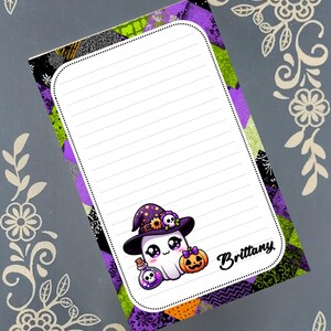May include: A lined notepad with a Halloween theme. The notepad features a cartoon ghost wearing a witch hat, holding a potion bottle and a pumpkin. The background has a patchwork design in purple, green, and black. The name "Brittany" is written on the notepad.