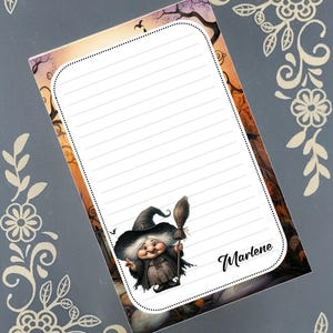May include: A lined notepad with a cartoon witch illustration. The witch is wearing a black hat and holding a broom. The notepad has the name "Marlene" written on it.