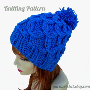 Może przedstawiać: Żywy niebieski dzianinowy kapelusz z teksturowanym wzorem i pasującym pomponem. Kapelusz jest prezentowany na głowie manekina. Słowa "Knitting Pattern" znajdują się u góry obrazu. Strona internetowa "yarntwisted.etsy.com" znajduje się na dole.