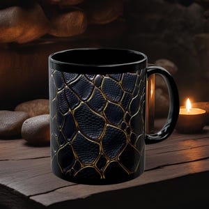 May include: Black ceramic mug with a gold snakeskin pattern. The mug has a large handle and is ideal for hot drinks.
