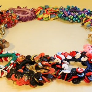 May include: A circle of colorful bracelets made from buttons. The bracelets are arranged in a circle on a white surface. The bracelets are made from a variety of buttons, including plastic, metal, and wood. The bracelets are all different colors, including red, blue, green, yellow, and white. The bracelets are all different sizes, and some of them have a pattern of buttons.