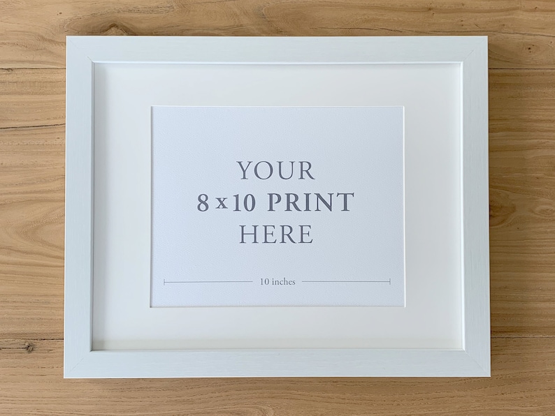 May include: White picture frame with a white mat, ready to display an 8x10 inch print. The frame has a simple, modern design and is perfect for showcasing your favorite photos or artwork.