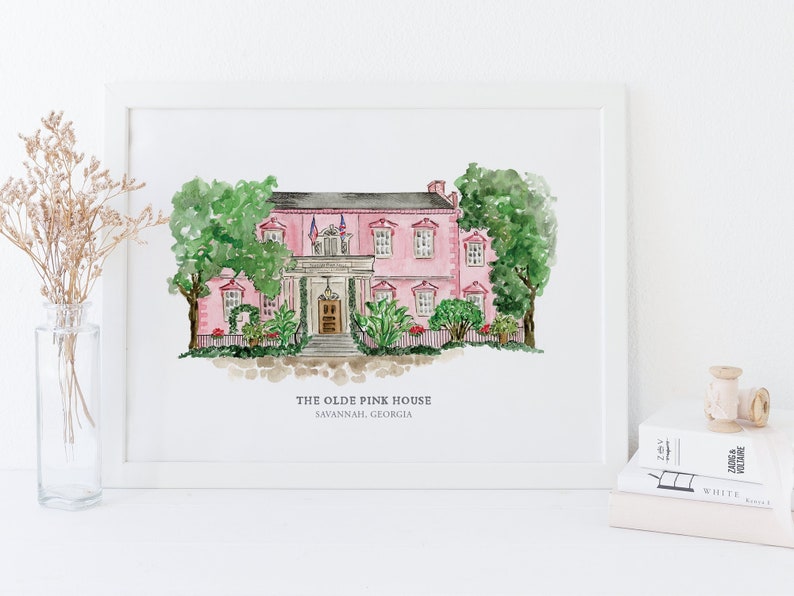 May include: A watercolor painting of a pink house with white trim and green trees. The house has a white picket fence and a porch with a door. The text "THE OLDE PINK HOUSE SAVANNAH, GEORGIA" is below the house.