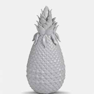 May include: A grey ceramic pineapple ornament. The pineapple has a textured surface with a diamond pattern and detailed leaves at the top. The ornament is a decorative item.