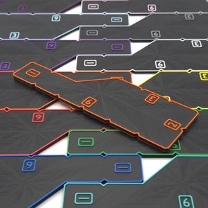 May include: Black rectangular game pieces with colored borders and white numbers. The pieces have orange, green, blue, purple, and yellow borders. The numbers include 0, 2, 3, 6, and 9. The pieces are arranged in a grid.