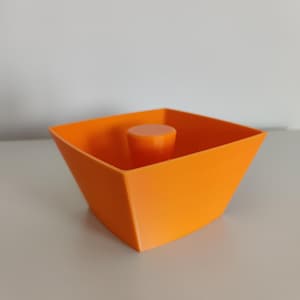 Peut inclure: Un pot de fleurs carré de couleur orange vif avec un insert rond orange au centre.