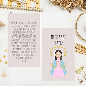 May include: Two printable cards with a pink background. The card on the left features a prayer to the Virgin Mary. The card on the right features a cartoon image of the Virgin Mary with a halo of stars and the text "MEMORARE PRAYER".