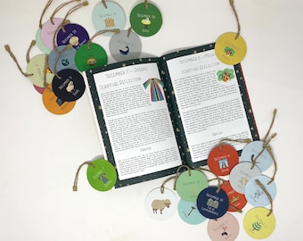 May include: A devotional book open to pages titled December 7 and December 8, surrounded by numerous circular cardboard ornaments in various colours. Each ornament features a date, a small illustration, and a name or title attached with twine.