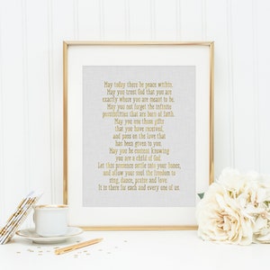 May include: A framed print with a gold-colored inspirational quote about peace, trust, and love. The quote is printed on a textured, light gray background. The frame is gold and has a white mat.