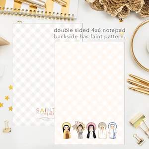 May include: A double-sided notepad with a faint pattern on the back. The front side features a colorful illustration of saints with the text "SAINT of all of all" and a copyright symbol.