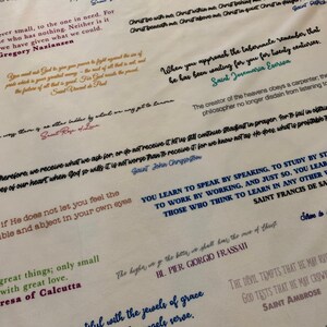 May include: A white background with inspirational quotes from various saints and religious figures. The quotes are written in different colors of ink, including blue, red, green, and black. The text includes quotes from Saint John Chrysostom, Saint Teresa Benedicta of the Cross, Saint Rose of Lima, Saint Agnes, Saint Ambrose, Saint Patrick, Saint Vincent de Paul, Saint Francis de Sales, Saint Josemaria Escriva, and Mother Teresa of Calcutta.