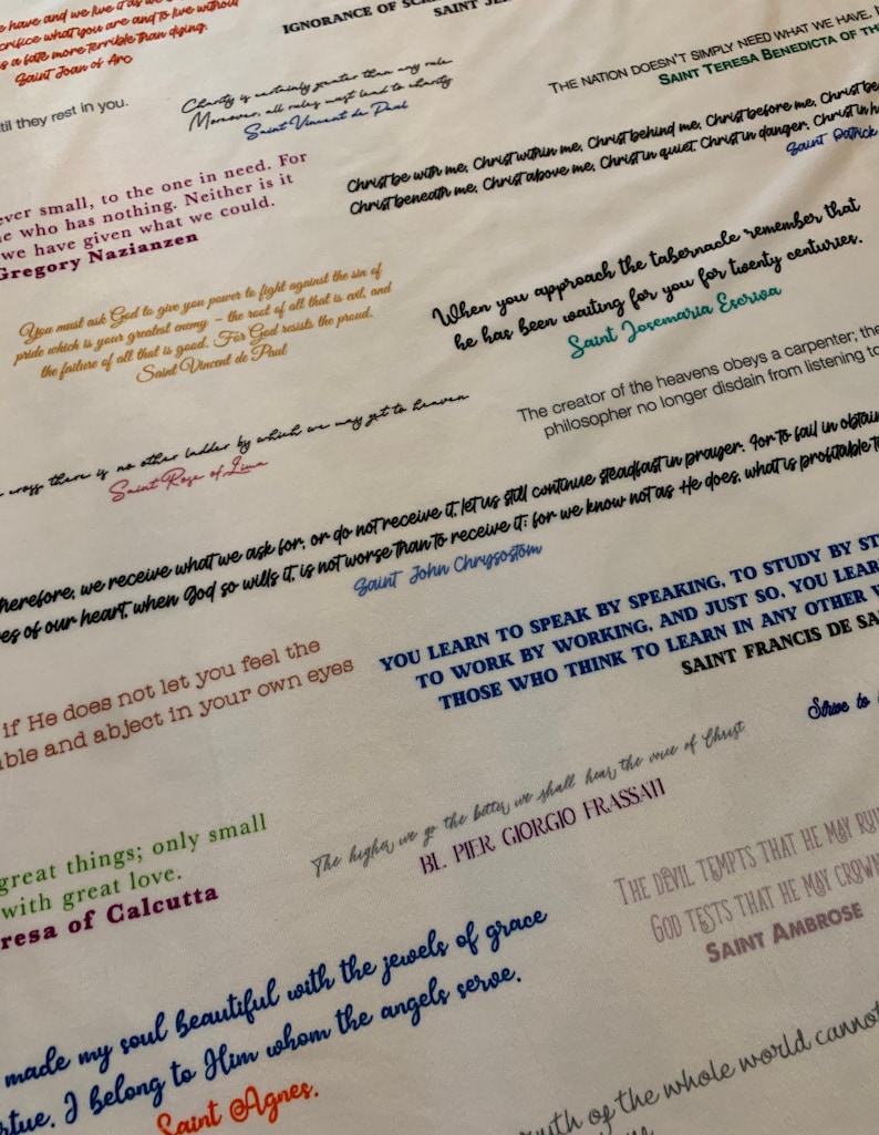 May include: A white background with inspirational quotes from various saints and religious figures. The quotes are written in different colors of ink, including blue, red, green, and black. The text includes quotes from Saint John Chrysostom, Saint Teresa Benedicta of the Cross, Saint Rose of Lima, Saint Agnes, Saint Ambrose, Saint Patrick, Saint Vincent de Paul, Saint Francis de Sales, Saint Josemaria Escriva, and Mother Teresa of Calcutta.