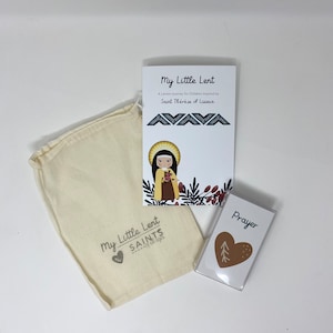 May include: A white drawstring bag with the text "My Little Lent Saints" printed on it. A white booklet with the text "My Little Lent A Lenten Journey for Children Inspired by Saint Thérèse of Lisieux" is next to the bag. A small white card with the text "Prayer" is in front of the bag.