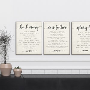 May include: Three framed prints with white backgrounds and black text. The prints feature the Hail Mary, Our Father, and Glory Be prayers. Each print has the word "amen" at the bottom.