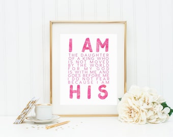 May include: A framed print with a pink watercolor design and the text "I AM THE DAUGHTER OF A KING WHO IS NOT MOVED BY THE WORLD FOR MY GOD IS WITH ME AND GOES BEFORE ME I DO NOT FEAR BECAUSE I AM HIS"
