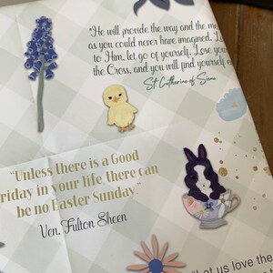 Pu&ograve; includere: Uno sfondo a scacchi verde e bianco con citazioni ispiratrici sulla Pasqua. Le citazioni sono di Santa Caterina da Siena e Ven. Fulton Sheen. L'immagine include anche illustrazioni di un pulcino, un coniglio e fiori.