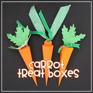 May include: Three orange carrot-shaped treat boxes with green paper leaves and green and white checkered ribbon. The text "CARROT + TREAT boxes" is displayed in white and orange. The boxes are on a black background.