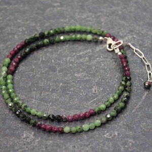 May include: A double-strand necklace with green, pink, and black beads. The necklace has a silver clasp and extender chain.