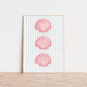 Könnte beinhalten: Gerahmter Druck mit drei rosa Muschelbildern, die vertikal angeordnet sind. Der Hintergrund hat hellblaue und weiße vertikale Streifen. Das Kunstwerk wird auf einem Holzboden ausgestellt.