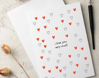 May include: A white card with a red and black heart pattern. The card says "i love you very much".