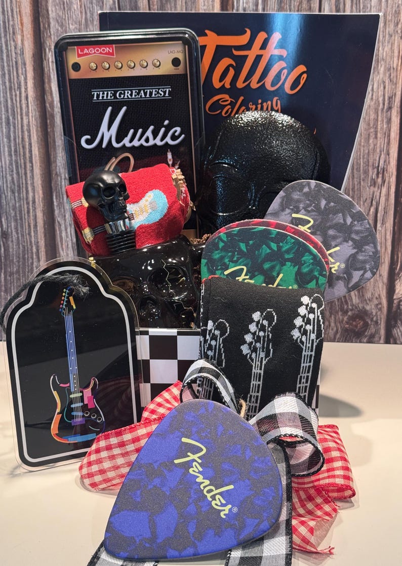 May include: A gift basket with a rock and roll theme. Includes a black skull bottle stopper, guitar picks, a guitar-shaped ornament, and a "Tattoo Coloring" book. The basket is decorated with a red and white checkered ribbon.
