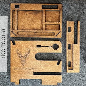 May include: A wooden phone stand with a deer silhouette and the name "Lucas Brown" engraved. The stand has a separate tray with compartments for organizing items. The stand is easy to assemble and requires no tools.